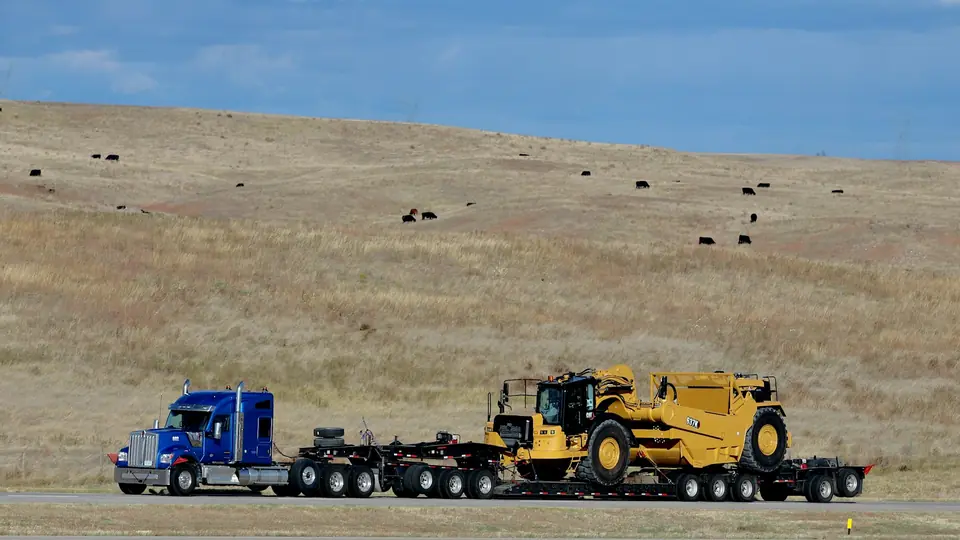 Semi-truck hauling heavy equipment on a lowboy trailer